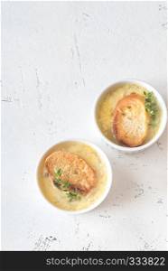 Two bowls of onion soup with fresh thyme on the table