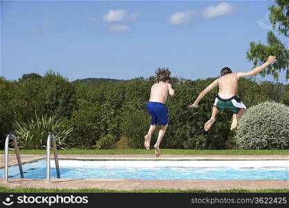 Two boys (6-11) jumping into pool, back view