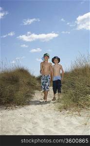Two boys (6-11) walking in sand dunes with fishing net