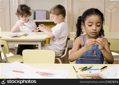 Two boys and a girl drawing in a classroom