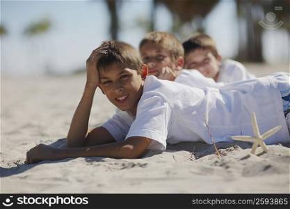 Two boys and a teenage boy lying on the beach
