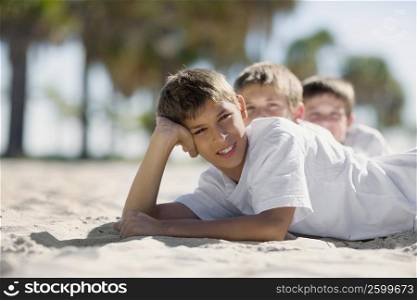 Two boys and a teenage boy lying on the beach