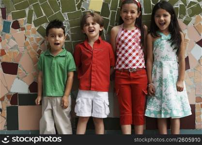 Two boys and two girls leaning against a wall