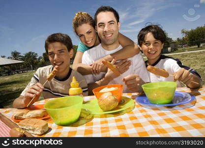 Two boys eating sausages with their parents in a picnic