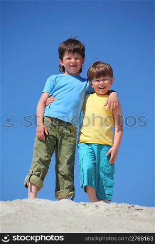 Two boys embrace each other on sand