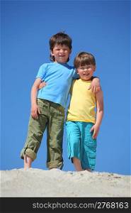 Two boys embrace each other on sand