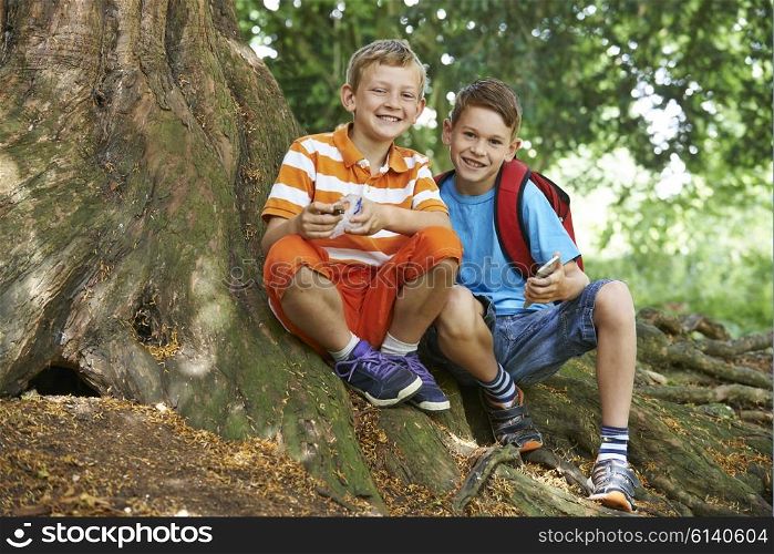 Two Boys Geocaching In Woodland
