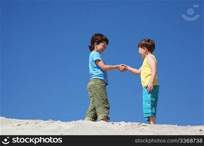 Two boys greet on sand