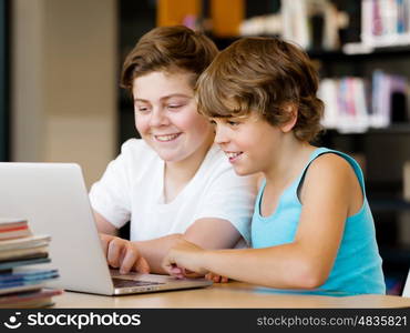 Two boys in library with notebook. Two boys in library