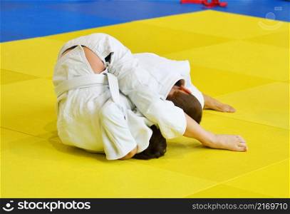 Two Boys judoka in kimono compete on the tatami
