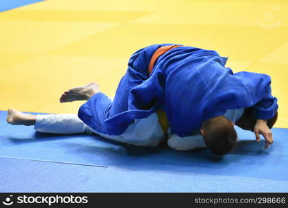 Two Boys judoka in kimono compete on the tatami