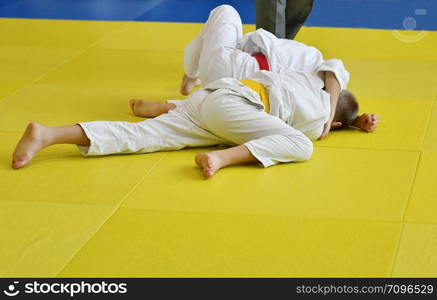 Two Boys judoka in kimono compete on the tatami