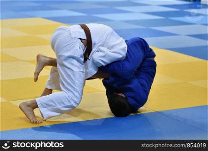 Two boys judoka in kimono compete on the tatami