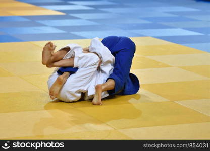 Two boys judoka in kimono compete on the tatami