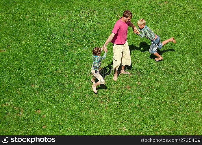 Two boys play with the adult a lawn. The top view.