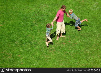 Two boys play with the adult a lawn. The top view.