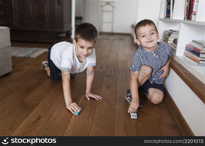 two boys playing with car toys hardwood floor