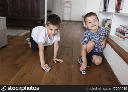two boys playing with car toys hardwood floor