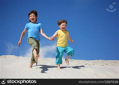 Two boys run on sand