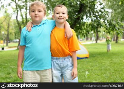 Two boys standing next to each other in the summer park