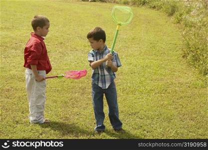 Two boys standing on the lawn and holding butterfly nets