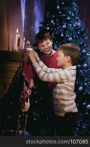 Two Brothers putting Milk and Cookies on the Fireplace for Santa Claus in Christmas Night