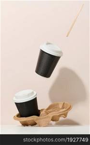 two brown cardboard cups with a white plastic lid. Disposable tableware levitates against a beige background. Coffee shop template