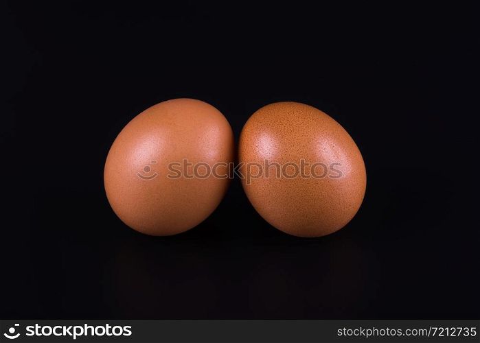 two brown eggs close-up on a black background. brown eggs