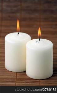 Two burning candles on a bamboo napkin