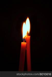 two burning candles on a black background