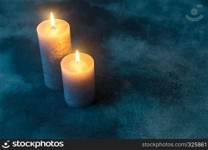 Two burning candles on navy blue background