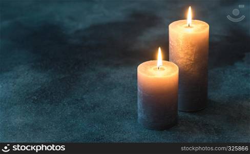 Two burning candles on navy blue background
