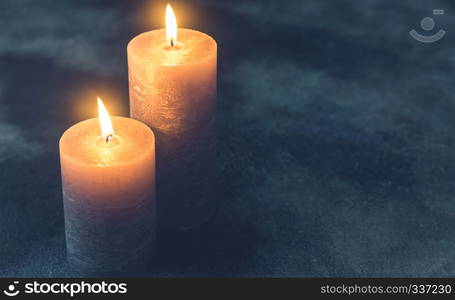 Two burning candles on navy blue background