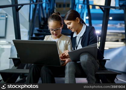 Two business children with laptop and paper document working together sitting on stairs. Two business children working together on stairs