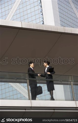 Two Business Colleagues Shaking Hands Outside Office Building