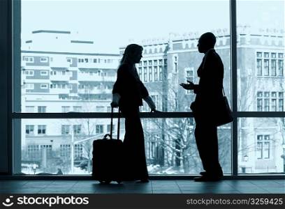 Two business colleagues silhouetted in a large window.