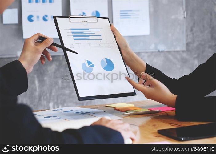 two business executives analyzing data paper on a clipboard at meeting room
