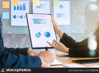 two business executives analyzing data paper on a clipboard at meeting room