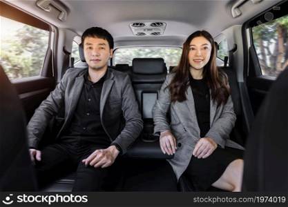 two business man and woman sitting at the back seat of a car