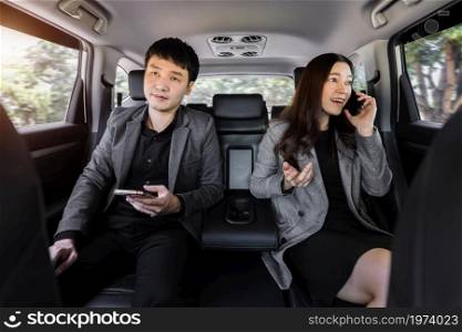two business man and woman using mobile phone while sitting at the back seat of a car