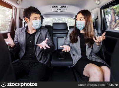 two business man and woman wearing face mask for protect covid-19 (coronavirus) and talking while sitting at the back seat of a car