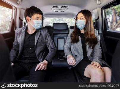 two business man and woman with face mask for protect covid-19 (coronavirus) while sitting at the back seat of a car