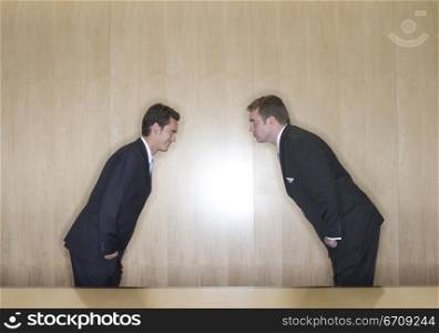 Two business men bow to each other in the board room