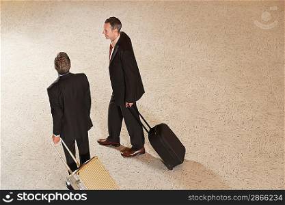 Two business men pulling suitcases in lobby