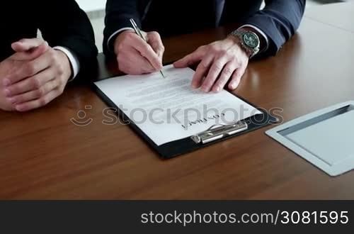 Two business men signing a contract close up view