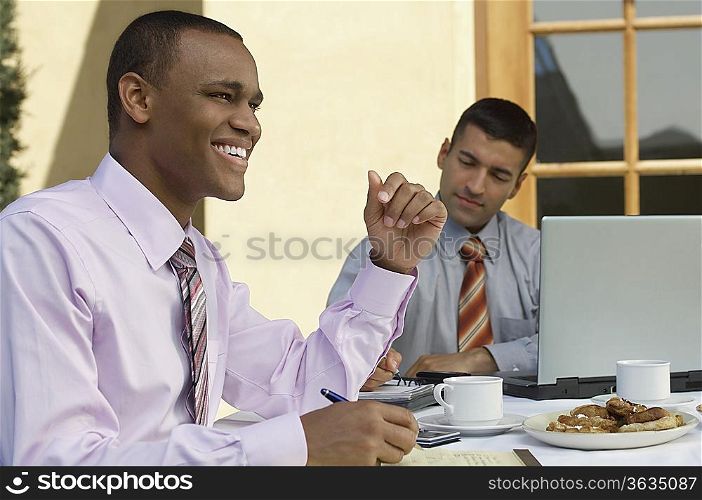 Two business men working at outdoor cafe table