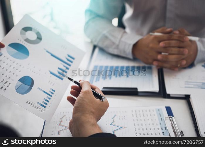 Two business partnership coworkers analysis cost work progress and gesturing with discussing a financial planning graph and company financial during a budget meeting in office room.