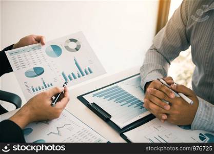 Two business partnership coworkers analysis strategy and gesturing with discussing a financial planning graph and company budget during a budget meeting in office room.