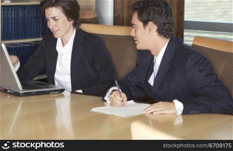 Two Business People discussing their work with a laptop in the board room