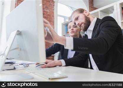 Two business people looking at monitor. Two business people looking at monitor sitting in office